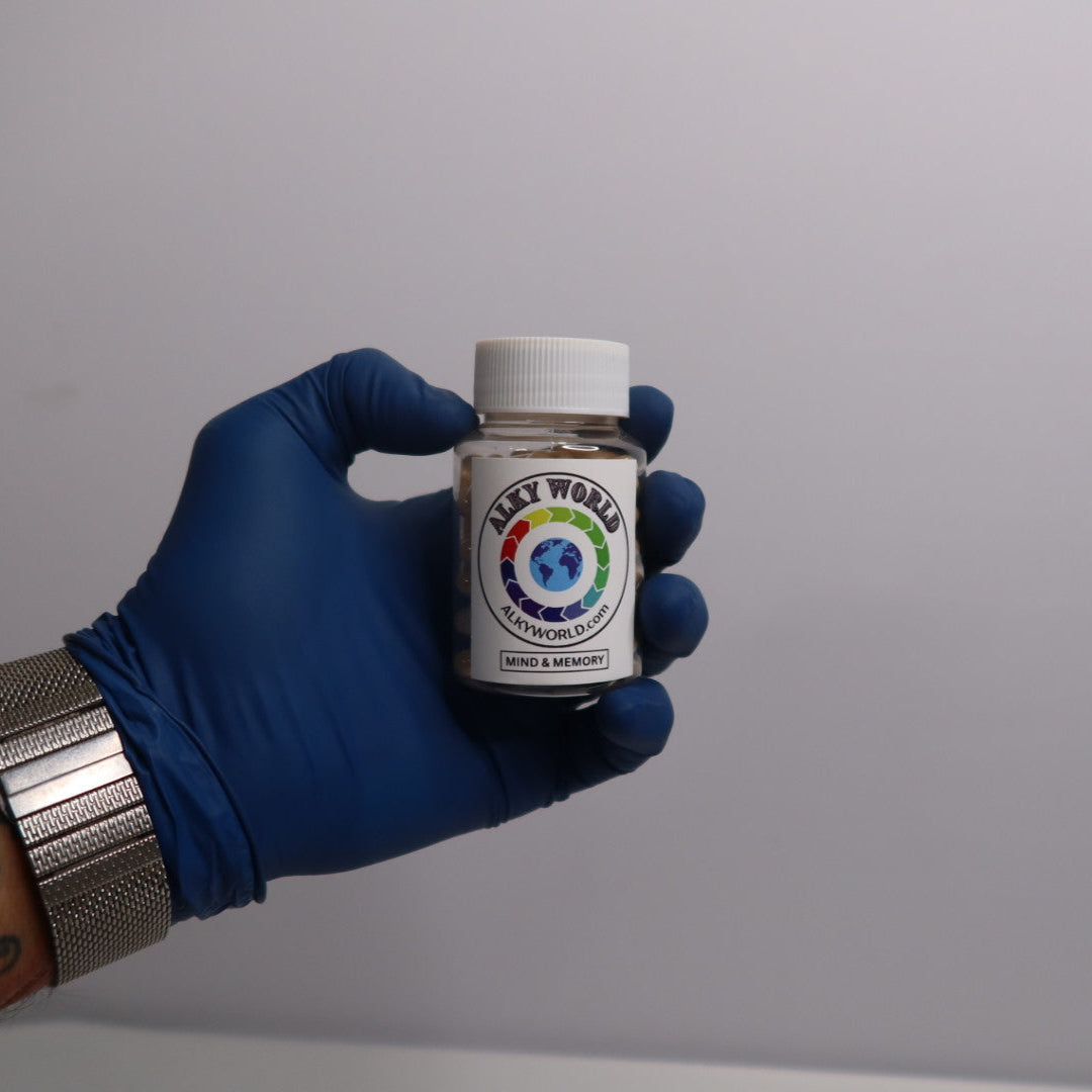 Hand wearing a blue glove holding a small bottle labeled 'Alkyworld' Mind & Memory Capsules