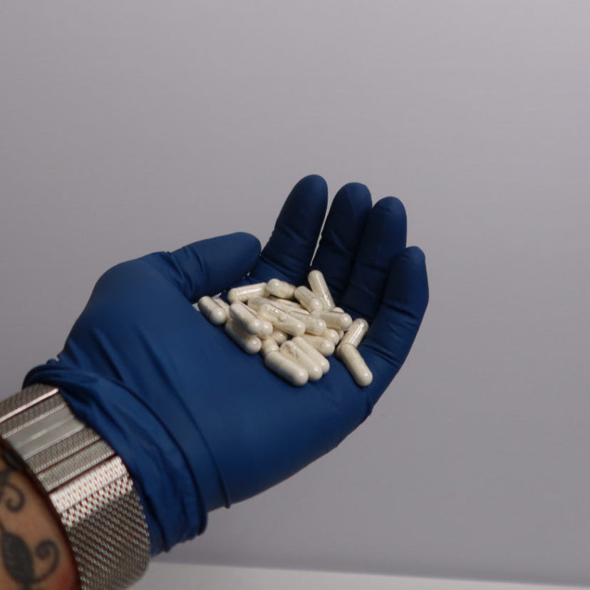 Hand wearing a blue glove holding Irish Seamoss Capsules